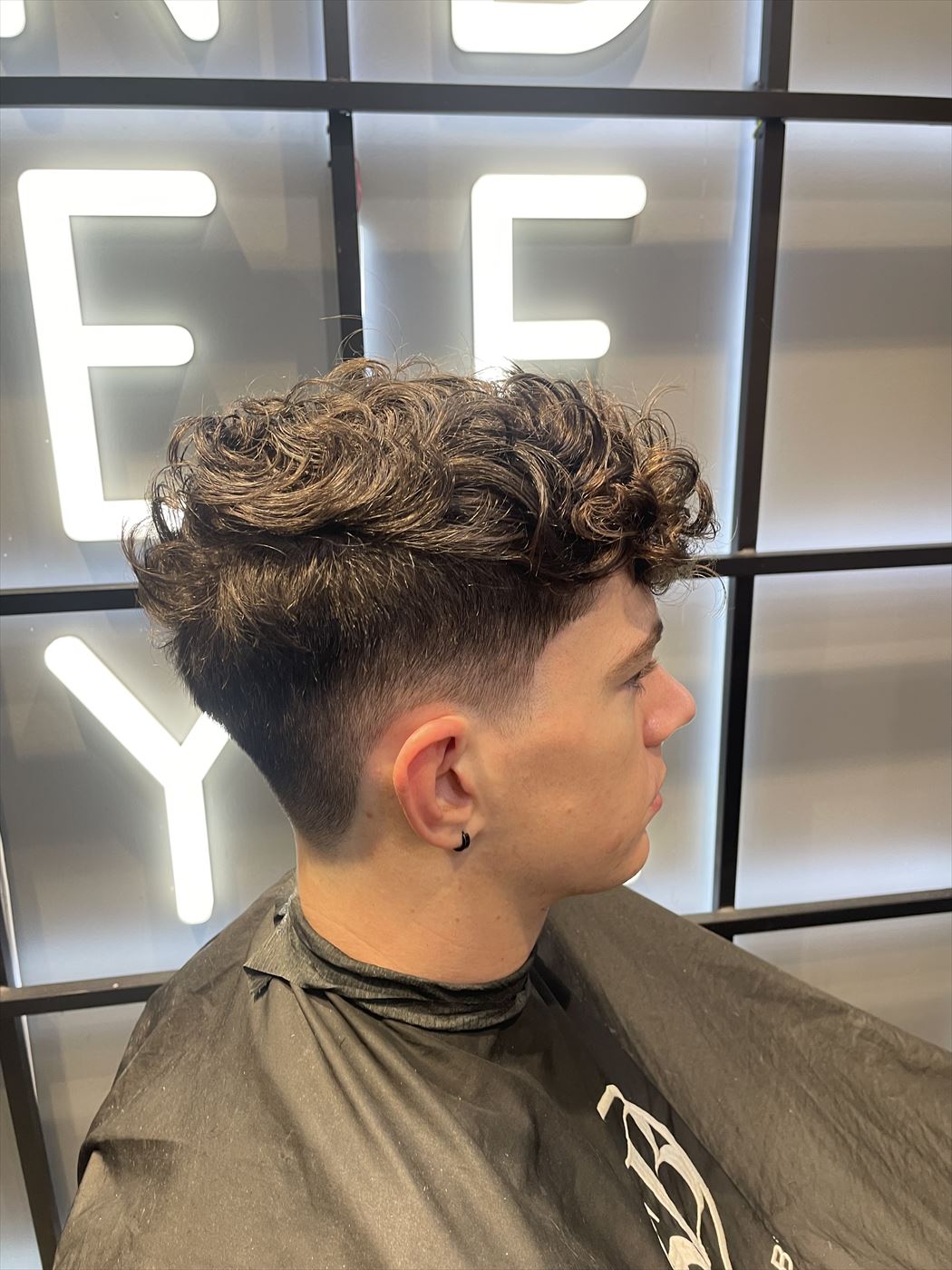 Curly textured top with a low drop fade